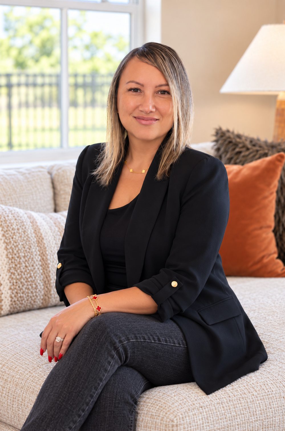 Jenn Pagsolingan, REALTOR® serving the East Bay and Tri-Valley, sitting on a sofa in a bright living room